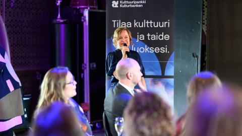 Karoliina with a microphone in her hand speaking at the launch of the renewed Culture Bank 30.9.2025