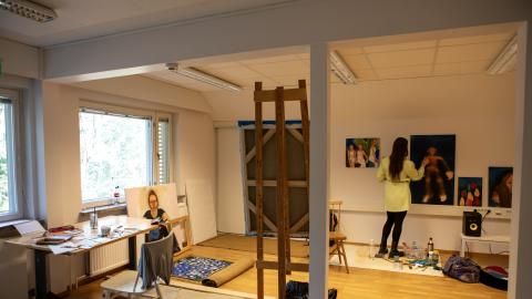 Taiteilija maalaa teosta työhuoneellaan.