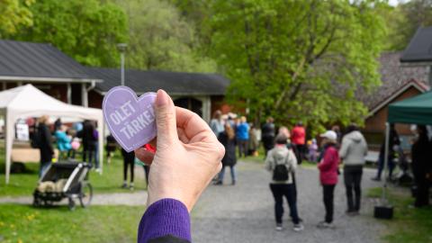 A summer event with people visible in the background. In the foreground, a hand holding a sticker with the text "You are important."