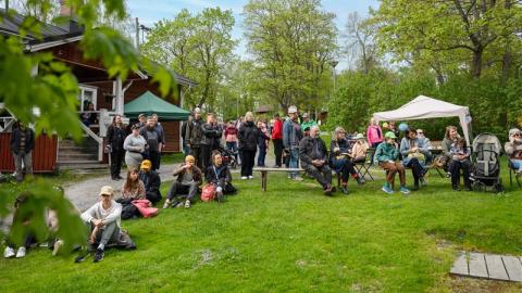 Iso joukko ihmisiä istuu ulkona odottamassa tapahtuman alkua. 