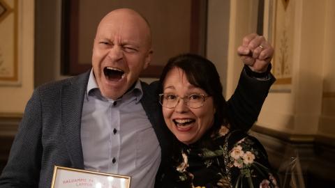 Kaksi henkilöä juhlistaa iloisesti saamaansa palkintoa. 