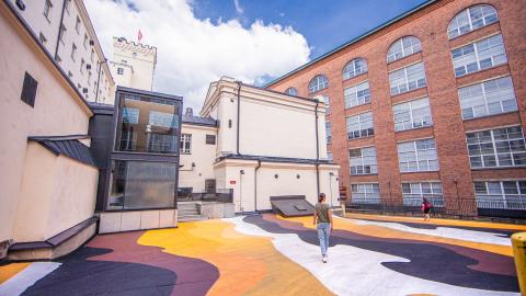 Nainen kävelee Finlaysoninn alueella, jossa värikkääksi maalattu maa.