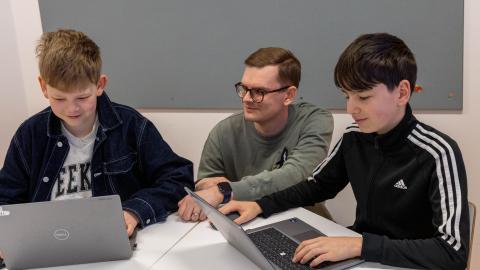Aleksi Huttu guides two students at the table on how to use Digital Models.