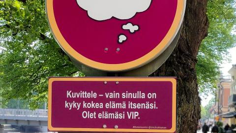 Punaisia liikennemerkin tyylisiä kylttejä puun kyljessä. 
