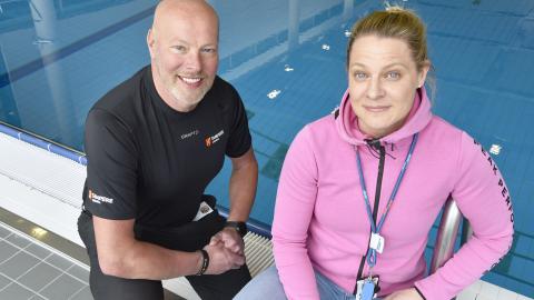 A man and a woman smiling in front of a swimming pool.