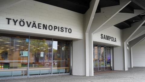 Rakennuksen sisäänkäynti. Kolme isoa ikkunaa. Seinässä teksti "Työväenopisto".