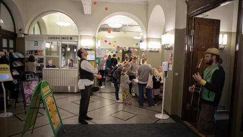 People have flocked to the event. A juggler is throwing balls. A musician plays the guitar.