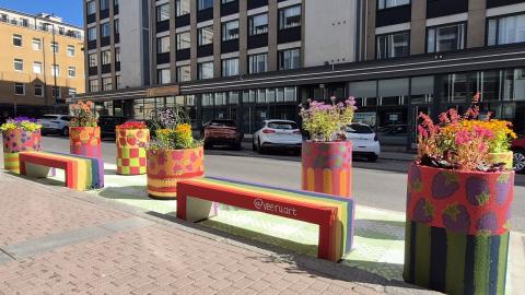 Rainbow-colored concrete benches, large plant pots with berry-themed paintings, and asphalt painted to look like a picnic blanket on Hallituskatu.