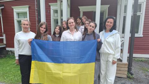Johanna Kirjavainen stands with young people from Kiova, holding the Ukrainian flag, at the Sorja summer camp.