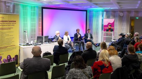 Four directors of the city are seated in front of the audience.