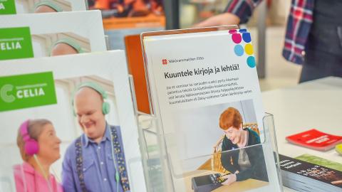 Esitteitä telineessä. Pöydällä kirjanmerkkejä.