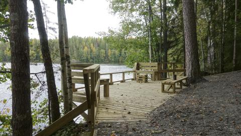 An accessible wooden fishing platform by the lake in a wooded setting.