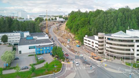 Kuvassa katu, jossa työmaa. Ympärillä rakennuksia ja vihreyttä.