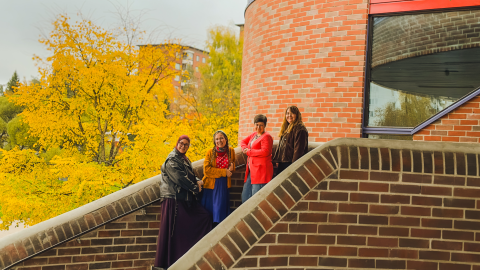 Staff from the association Setlementti Tampere standing cheerfully on the steps of the Hervanta Leisure Centre.