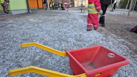 Kuurainen päiväkodin piha ja muoviset kottikärryt.