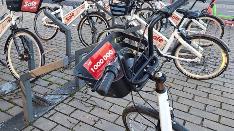 City bikes at a bike station. A sign marking the one millionth journey is attached to the basket of the bike in the foreground.
