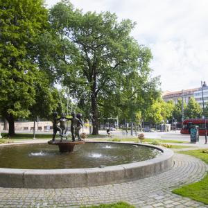 A fountain in Pyynikki Church Park, with a tram in the background.