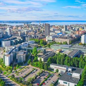 Ilmakuvanäkymässä Tampereen keskusta kesäaikaan, aurinko paistaa, taivas on sininen, puut vihreitä ja taustalla korkeita rakennuksia..