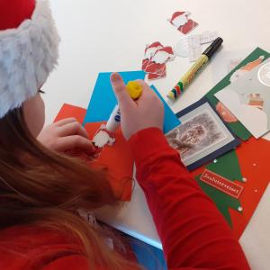 A youngster in an elf hat makes brightly coloured Christmas cards for the Christmas Post to the Elderly campaign.