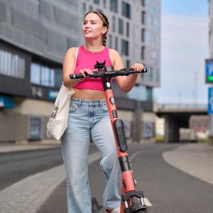 Young woman with an electric scooter looking at the surroundings