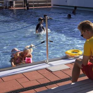 Uima-altaassa pieniä lapsia uimassa ja uimavalvoja 