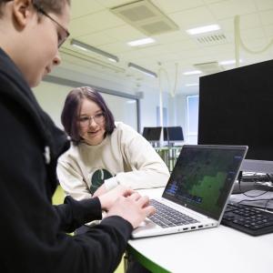 Kaksi nuorta kannettavan tietokoneen äärellä.