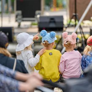 Kolme lasta katsomassa lavaohjelmaa Puistofiesta-tapahtumassa.