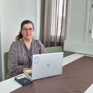 Terhi Lehtinen istuu pöydän ääressä ja pöydällä on kannettava tietokone