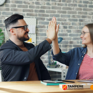 Vanhempi työntekijä ja nuori hymyilevät ja paiskaavat kättä läppärin äärellä.