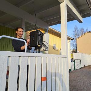 Tutkija asentamassa mittalaitteita päiväkodin kuistilla.