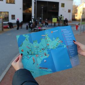 Seikkailukartta lähikuvassa, taustalla päiväkodin pihassa vilskettä.