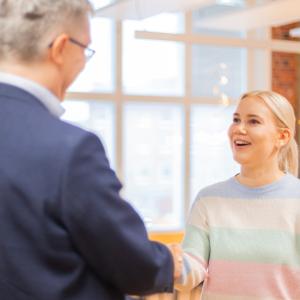 Nuori henkilö kättelee vanhempaa henkilöä.