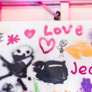 Iloisen näköisiä hahmoja, sydämiä, aurinko ja sanat &quot;Love&quot; ja &quot;Jee&quot; graffitiseinällä.