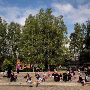 Puistoa, ihmiset istuskelevat portailla. 