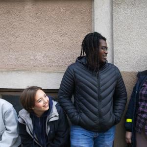 Joukko nuoria iloisena vaalean seinän edessä