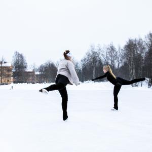 Kaksi tyttöä luistelee ulkokentällä.
