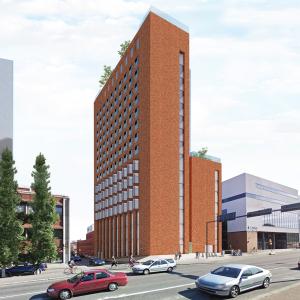 The image shows a city environment and a redbrick high-rise building that includes a lower section.