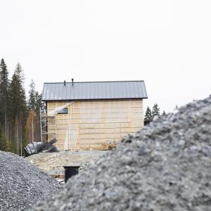 Sorakasan takaa näkyy keskeneräisen omakotitalon rakennustyömaa metsikön laidalla.