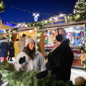 Two people enjoying the Christmas market atmosphere after dark.