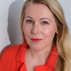 Irene looks straight into the camera wearing a bright red shirt.