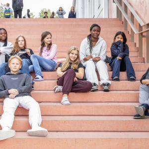 nuoria istumassa koulun rappusilla