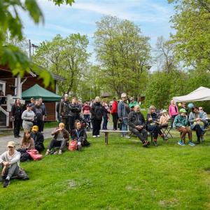 Iso joukko ihmisiä istuu ulkona odottamassa tapahtuman alkua. 