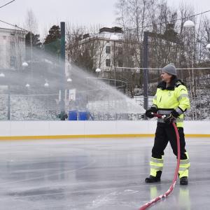 Kenttätyöntekijä jäädyttää jäätä letkulla 