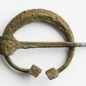 Metallinen puolikuunmuotoinen esine, jonka keskellä on terävä piikki.