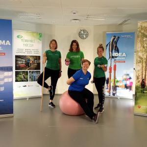 Four smiling women pose with sports equipment.