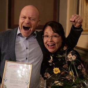 Kaksi henkilöä juhlistaa iloisesti saamaansa palkintoa. 