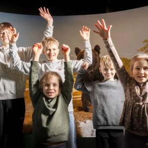 Lapset hurraavat luonnontieteellisessä museossa kädet ylhäällä.