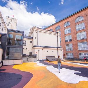 Nainen kävelee Finlaysoninn alueella, jossa värikkääksi maalattu maa.