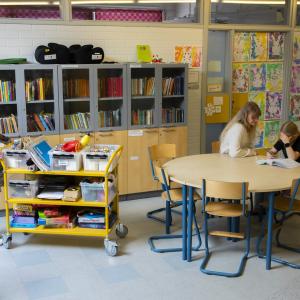 Two teachers are helping a student with homework at school.