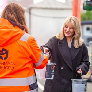 Jätehuollon työntekijä ottaa vastaa maalipurkkijätteet tuojalta.